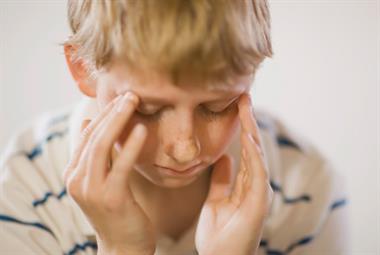 Young boy holding his head in his hands