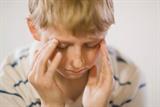 Young boy holding his head in his hands