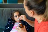 A child being given medicine by her mother