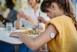 Young girl with continuous glucose monitoring sensor on arm eating food