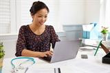 A young female GP typing on a  laptop