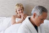 Older unhappy man sitting on edge of bed